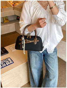 Détail du sac bowling en cuir noir avec breloque chocolat et poignées marron élégantes
