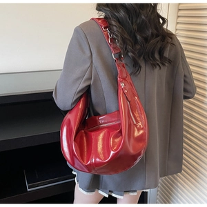 Close-up of a red glossy patent leather hobo bag styled with a grey business suit