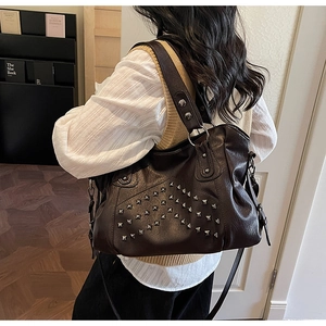 Detail view of coffee brown tote bag with silver rivets and wide strap shown on shoulder