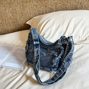 Close-up of vintage blue denim shoulder bag with floral embroidery and Y2K metal zippers
