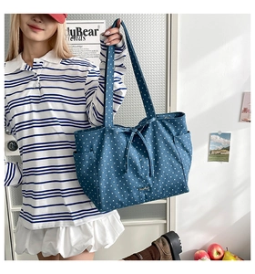 Detail showing blue canvas tote bag with white star pattern and bow drawstring detail