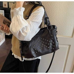 Detailed view of vintage studded leather tote bag with silver rivets and litchi texture