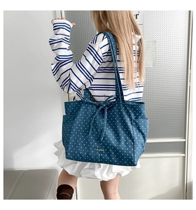 Detail of navy tote bag with white stars and bow strap shown on a shoulder