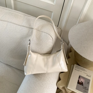 Close-up of cream white pleated PU leather handbag with silver buckle on a cozy sofa