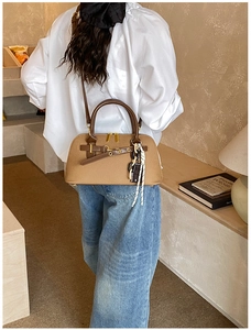 Détail du grand sac bowling marron avec pendentif tressé et finitions métalliques dorées