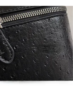 Close-up of black ostrich pattern leather bag with silver metal zipper detail