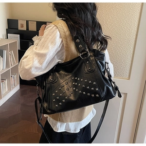 Detailed close-up of a black faux leather tote with silver stud rivets and a strap