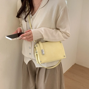 Detail of light yellow crossbody pillow bag with silver rivets and metal lock