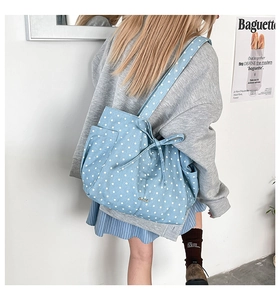 Detail of light blue tote bag with white star prints, side pocket and bow accent