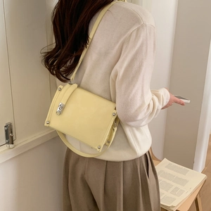 Detail view of light yellow leather pillow bag with silver buckle on a person