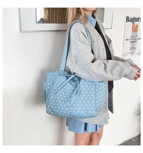Detail of light blue polka dot tote bag with star patterns and a decorative bow