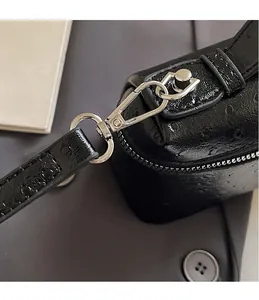 Detail of silver metal swivel hook and textured ostrich pattern leather bag material