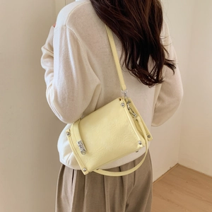 Detail of light yellow pleated leather crossbody bag with silver hardware on model
