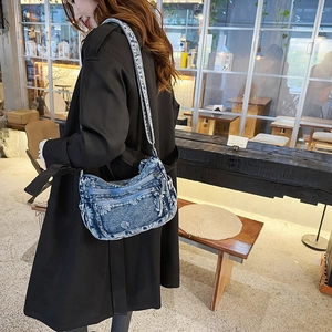 Detail shot of vintage denim crossbody bag featuring white floral embroidery and zippers