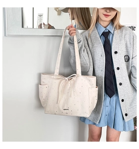 Close-up of beige tote bag with silver star patterns and delicate bow ribbon detail