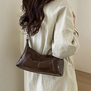 Close-up of retro brown shoulder bag with stitching detail on vintage waxy leather surface