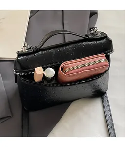 Detail view of the black ostrich-textured crossbody bag showing spacious interior space