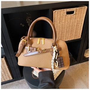 Détail du sac bowling marron avec anses en cuir et breloque décorative en chocolat