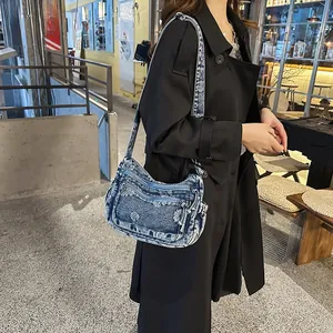 Detailed macro view of vintage denim shoulder bag with white floral embroidery and frayed edges