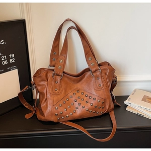 Detailed close-up of brown faux leather tote with vintage silver rivet studs on surface
