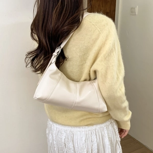 Model wearing a minimalist cream crescent underarm bag with adjustable leather strap