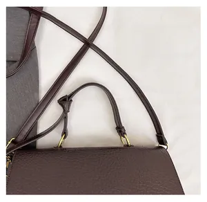 Gros plan sur la texture du cuir marron et les détails métalliques dorés du sac cabas