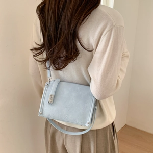 Detail of light blue crossbody bag with vintage wrinkled texture and silver buckle
