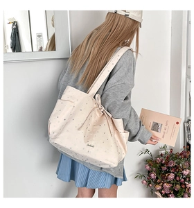 Detailed view of beige canvas tote bag with silver star patterns and bow drawstring detail
