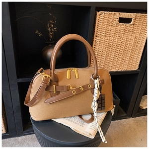 Détail d'un sac à main marron en toile et cuir avec ferrures dorées et breloque