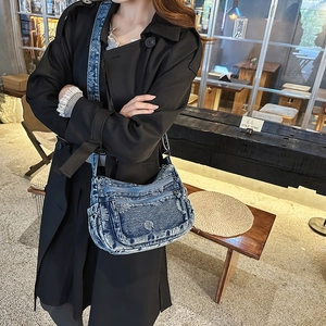 Detail view of denim crossbody bag with floral embroidery and multiple zipper pockets