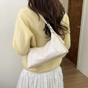Detail of a creamy white glossy underarm bag with vertical stitching and thin strap
