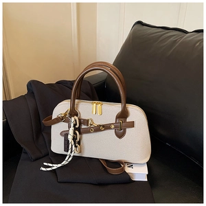 Détail du sac rétro en toile crème avec finitions en cuir marron et zip doré