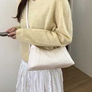 Close-up of cream retro shoulder bag with vertical decorative stitching and soft PU leather