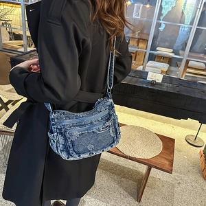 Detailed shot of retro blue denim crossbody bag with floral embroidery and multi-zip design