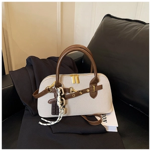 Vue détaillée du sac bowling en toile beige avec anses en cuir marron et boucles dorées