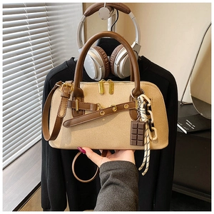 Détail du sac bowling en toile beige avec anses en cuir marron et pendentif chocolat