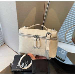 Detail of cream square box bag featuring ostrich embossed texture and silver zipper