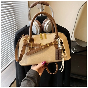 Détail du sac bowling en toile avec garniture en cuir brun et breloque en chocolat