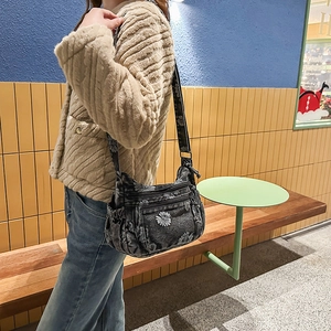 Detail of grey denim crossbody bag with daisy prints and functional zipper pockets