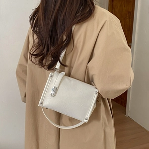 Detailed back view of a white wrinkled leather crossbody bag worn with a khaki trench coat