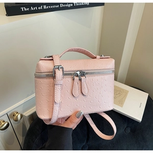 Detail of light pink mini box bag with ostrich texture finish and silver zipper closure