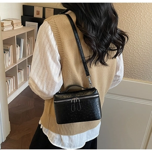 Detail view of black ostrich texture leather box bag with dual zipper and top handle