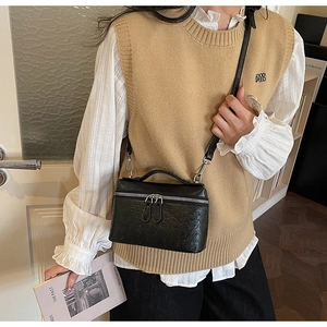 Detail of a minimalist black leather mini square bag featuring refined lychee texture