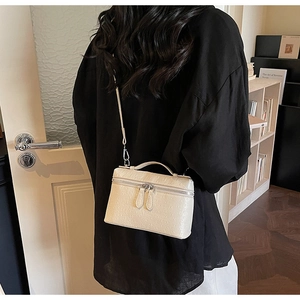 Detailed texture of off-white ostrich embossed handbag with silver dual zipper design