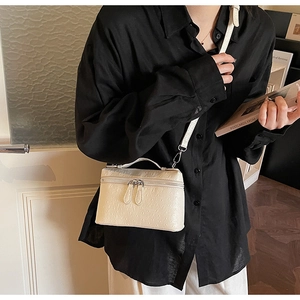 Model wearing ivory ostrich texture crossbody mini box bag with top handle and metal zippers