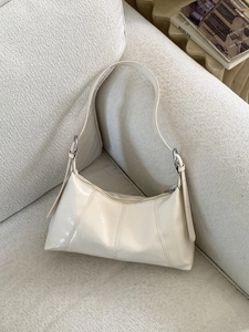 Retro cream white glossy hobo bag with silver ring hardware on a textured sofa