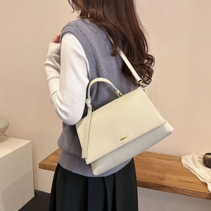 Vue latérale d'un sac cabas en cuir beige grainé porté en bandoulière sur un mannequin