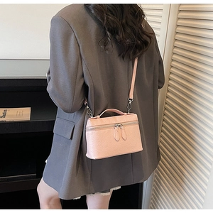 Pink ostrich pattern vanity bag shown on a model as a crossbody style with metal zippers