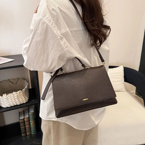 Détail du sac à bandoulière en cuir marron avec motif litchi et fermoir en métal doré
