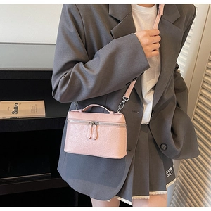 Detail of pink embossed leather box bag with silver zippers and removable shoulder strap